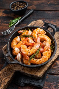Tavada karides kızartma, otlar ve sarımsaklı karides. Koyu ahşap arka plan. Üst görünüm