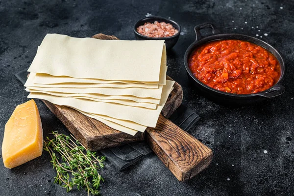 Raw Diferentes ingredientes para cocinar lasaña italiana en una mesa de cocina. Fondo negro. Vista superior — Foto de Stock