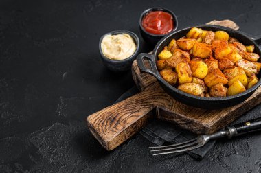 Patates bravas, baharatlı patates, kızarmış patatesli İspanyol yemeği ve baharatlı sarımsak sosu. Siyah arka plan. Üst Manzara. Boşluğu kopyala