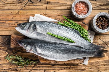 Tahta kesme tahtasının üzerinde biberiyeli taze deniz ürünü. Ahşap arka plan. Üst görünüm