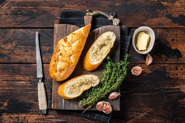 Toasted Garlic bread with herbs and butter on wooden cutting board. Wooden background. Top view — Stock Photo, Image