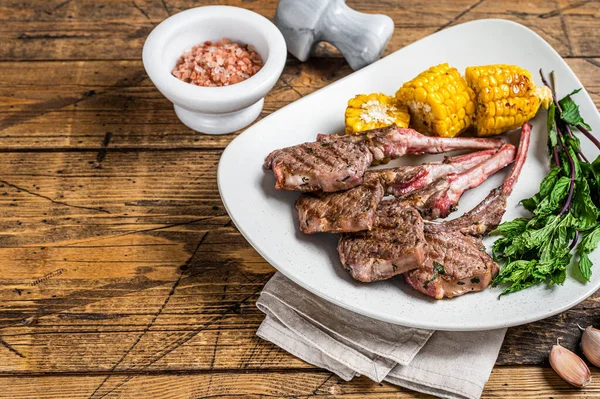 Grilled lamb chops steaks in a plate with corn and tomato. wooden background. Top view. Copy space — Stock Photo, Image
