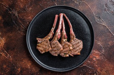 Barbekü ızgara kuzu pirzola bifteği tabakta. Karanlık arka plan. Üst görünüm