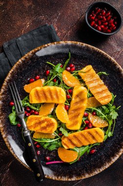 Izgara Halloumi peynirli, roka, portakal ve nar soslu yaz salatası. Karanlık arka plan. Üst görünüm