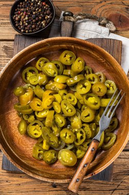 Jalapenolar eski ahşap tabakta turşu ve dilimlenmiş. Ahşap arka plan. Üst görünüm