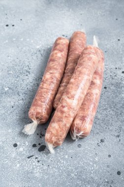 Mutfak masasında çiğ sosis var. Gri arka plan. Üst görünüm