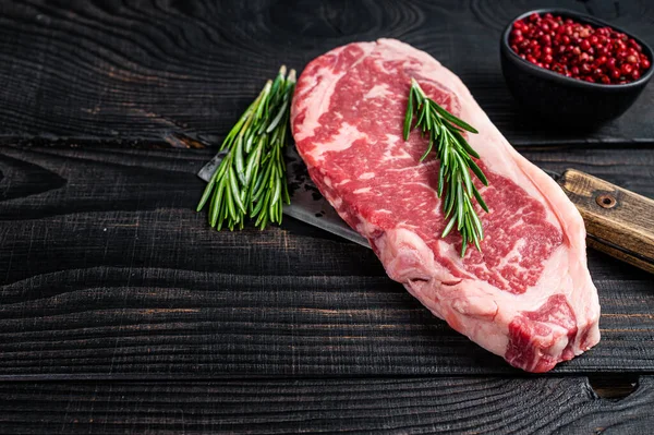 Fresh Raw new york strip beef steak on a butcher meat cleaver. Black wooden background. Top view. Copy space — Stock Photo, Image