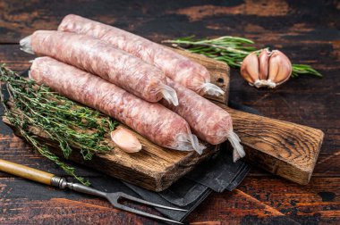 Tahtaya domuz eti konmuş çiğ sosisli sandviç. Karanlık ahşap arka plan. Üst görünüm