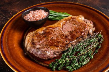 Kızarmış New York bifteği ya da kırsal bir tabakta striploin. Karanlık arka plan. Üst görünüm