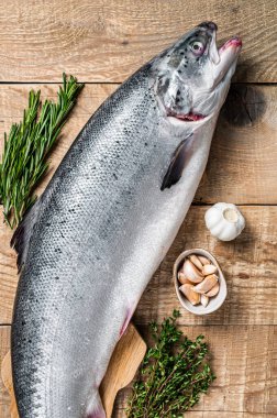 Tahta bir kichen masasında otlarla birlikte çiğ somon balığı. Ahşap arka plan. Üst görünüm