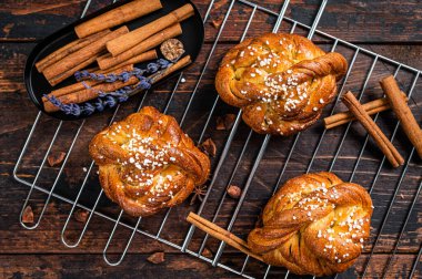 Ev yapımı taze tarçınlı çörek veya rulo, İsveç Kanelbullar. Koyu ahşap arka plan. Üst görünüm
