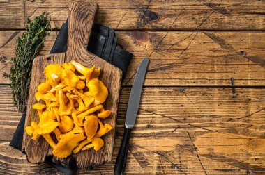Vahşi Çiğ, kesme tahtasında pişmemiş Chanterelles mantarı. Ahşap arka plan. Üst Manzara. Boşluğu kopyala