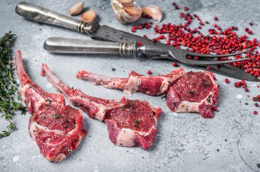 Biber ve kekik ile kasap masasında pişmemiş kuzu pirzolası bifteği. Gri arka plan. Üst görünüm