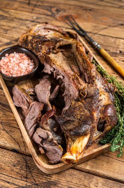 Ahşap tepside et çatalıyla omuz kesen kızarmış koyun eti. Ahşap arka plan. Üst görünüm