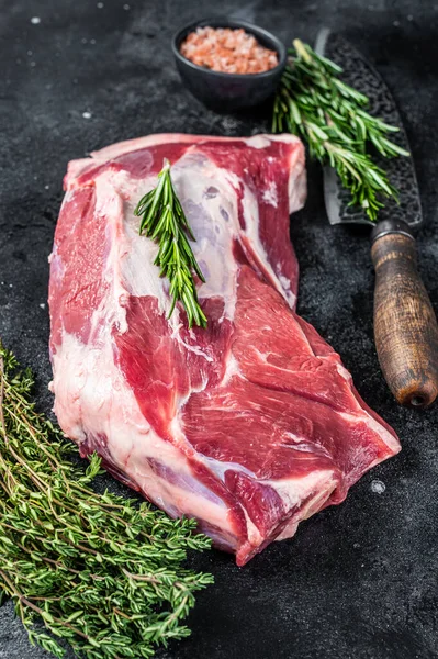 Fresh Raw lamb or goat shoulder meat with butcher knife. Black background. Top view