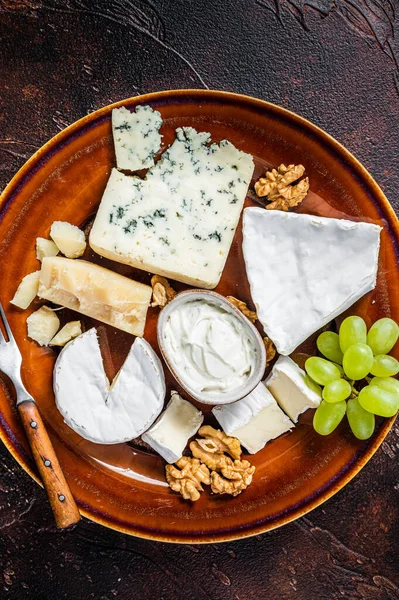 Prato de queijo com Brie, Camembert, Roquefort, queijo creme azul, uva e nozes. Fundo escuro. Vista superior — Fotografia de Stock