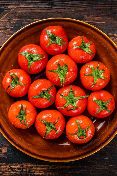 Röda mogna tomater på rustik tallrik. Mörk Trä bakgrund. Ovanifrån — Stockfoto