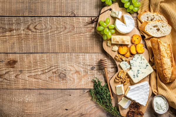 Queijo variado Brie, Camembert, Roquefort, parmesão, queijo creme azul com uva, figo, pão e nozes. fundo de madeira. Vista superior. Espaço de cópia — Fotografia de Stock