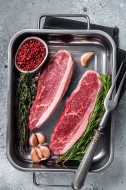 Çiğ sığır filetosu ya da tepside otlu biftek. Gri arka plan. Üst görünüm