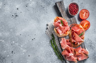 İspanyol Tapas, domatesli tost ve ahşap tahtada jambon dilimleri. Gri arka plan. Üst Manzara. Boşluğu kopyala