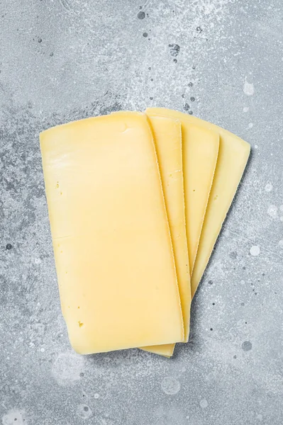 Raclette rebanadas de queso suizo sin cocer. Fondo gris. Vista superior — Foto de Stock