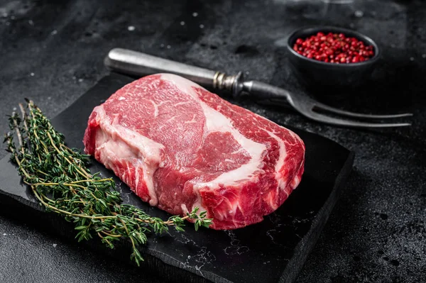 Ribeye syrový steak, hovězí mramorové maso s tymiánem a růžovou solí. Černé pozadí. Horní pohled — Stock fotografie