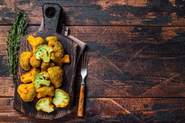 Tahta bir tahtanın üzerinde kırılmış brokoli bifteği. Koyu ahşap arka plan. Üst Manzara. Boşluğu kopyala