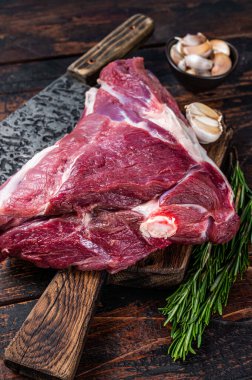 Et satırıyla kasap panosunda pişmemiş çiğ koyun budu. Koyu ahşap arka plan. Üst görünüm