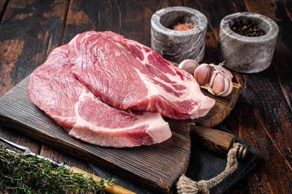 Macellaio crudo Bistecca di maiale da carne di filetto di collo crudo su tavola di legno con erbe. Sfondo in legno. Vista dall'alto — Foto Stock