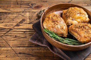 Biberiye ve bitkilerle birlikte ahşap bir tabakta kızarmış tavuk butları. Ahşap arka plan. Üst Manzara. Boşluğu kopyala