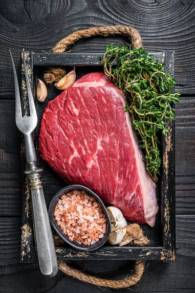 Syrový vrchní roštěnec hovězí steak z hovězí svíčkové nebo Picanha v dřevěném podnosu s bylinkami. Černé dřevěné pozadí. Horní pohled — Stock fotografie