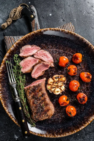 Lam sirloin filet vlees in plaat met gegrilde tomaat, schapenvlees gegrilde lendensteak. Zwarte achtergrond. Bovenaanzicht. — Stockfoto