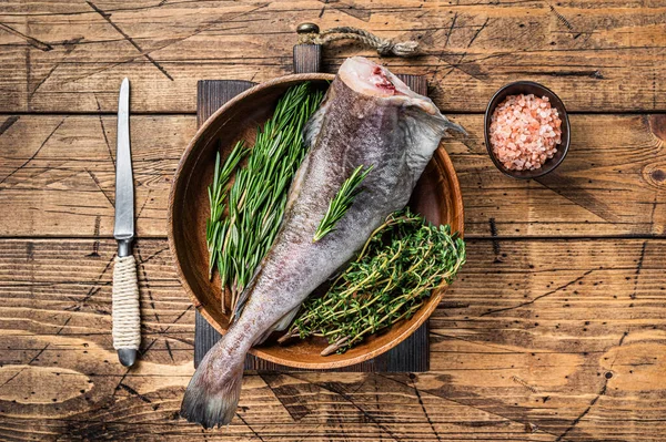 Çiğ morina ya da ahşap tabakta otlu morina balığı. Ahşap arka plan. Üst görünüm