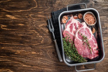 Mutfak tepsisinde taze et ve tuzlu kekik ile çiğ domuz bifteği. Ahşap arka plan. Üst Manzara. Boşluğu kopyala