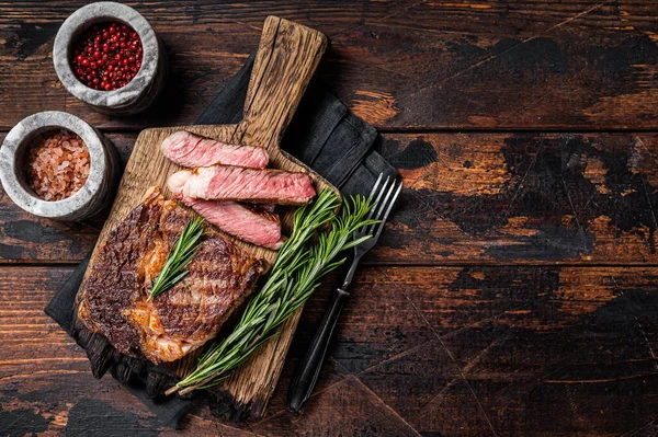 Filete de costilla rebanado y a la parrilla, carne de res de costilla de mármol en una tabla de madera. Fondo de madera. Vista superior. Copiar espacio — Foto de Stock