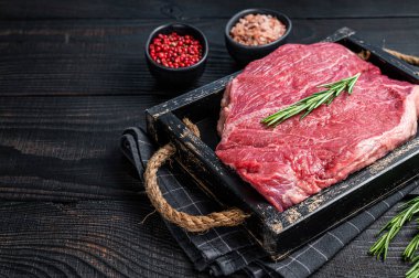 Tahta tepside otlu biftekler için çiğ biftek fileto. Siyah ahşap arka plan. Üst Manzara. Boşluğu kopyala