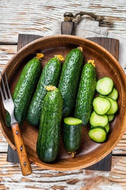 Tahta bir tabakta çiğ organik salatalık. Beyaz tahta arka plan. Üst görünüm