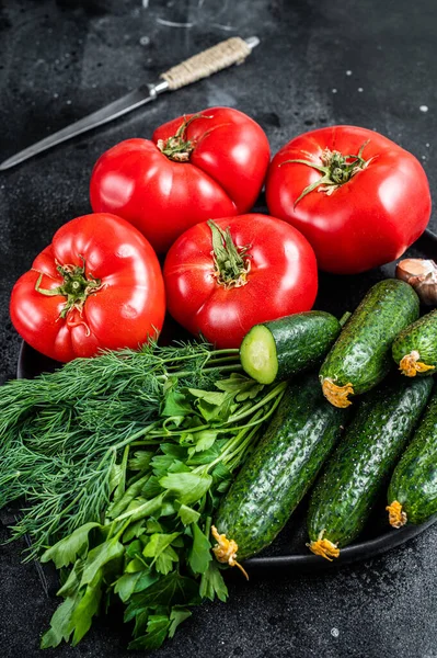 Färska grönsaker för sommarsallad, röda tomater, gurkor, persilja, örter. Svart bakgrund. Ovanifrån — Stockfoto