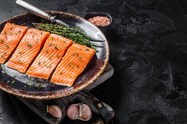 Somon fileto bifteği, kekik ve otlu çiğ balık. Siyah arka plan. Üst Manzara. Boşluğu kopyala