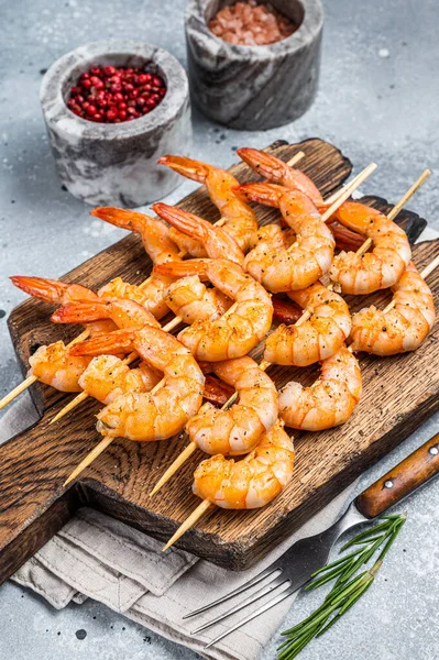 BBQ Gebratene Garnelen auf Spießen auf einem Holzbrett mit Kräutern. Grauer Hintergrund. Ansicht von oben — Stockfoto