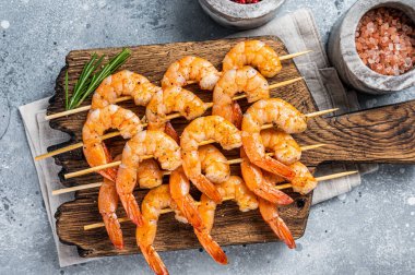 Ahşap bir tahtanın üzerinde karides şiş karides ve şifalı otlar. Gri arka plan. Üst görünüm