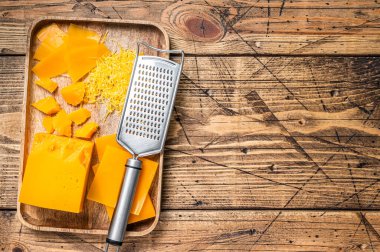 Çedar peyniri rendelenmiş ve ahşap bir tepside daldırılmış. Ahşap arka plan. Üst Manzara. Boşluğu kopyala