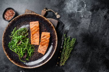 Barbekü vejetaryen yemeği - salatalı ızgara somon fileto bifteği. Siyah arka plan. Üst Manzara. Boşluğu kopyala