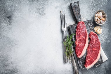Tahtada et bıçağı ve çatalla çiğ et bifteği. Beyaz arka plan. Üst Manzara. Boşluğu kopyala