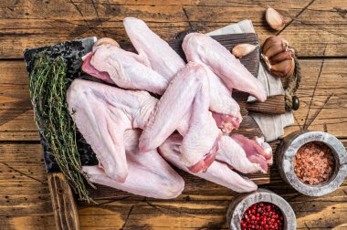 Kasap tahtasında çiğ ördek ya da tavuk kanadı. Koyu ahşap arka plan. Üst görünüm