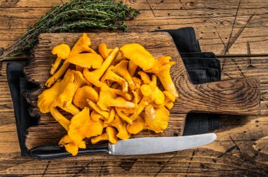 Vahşi Çiğ, kesme tahtasında pişmemiş Chanterelles mantarı. Ahşap arka plan. Üst görünüm