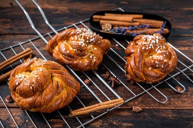 Ev yapımı taze tarçınlı çörek veya rulo, İsveç Kanelbullar. Koyu ahşap arka plan. Üst görünüm