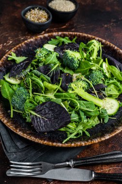 Taze roka yapraklı sağlıklı sebze salatası, marul, vegan salatası için ıspanak. Karanlık arka plan. Üst görünüm