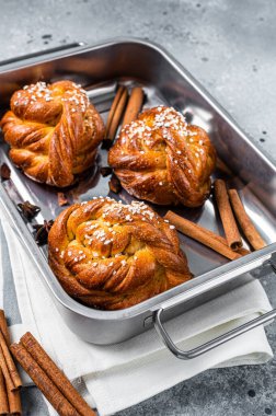 Kanelbullar - İsveç tarçını kabın içinde yuvarlıyor. Gri arka plan. Üst görünüm