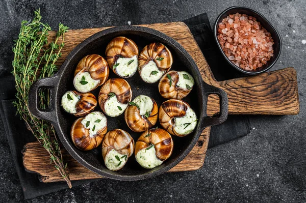 Delicatessen food - Bourgogne Escargot Snails with garlic butter in a pan. Black background. Top view — Stock Photo, Image